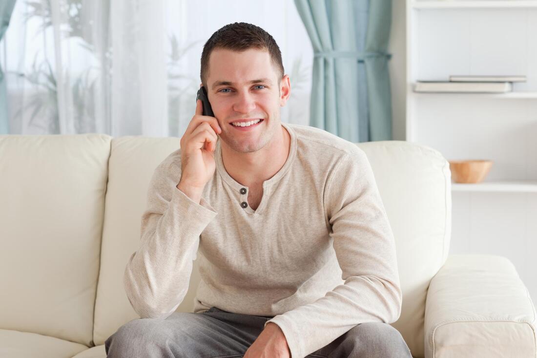 man sitting on the couch while talking to his phone